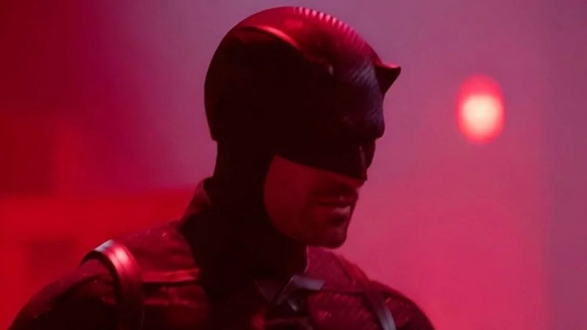 man in daredevil costume against a dimly lit purplish pink background