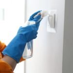 Woman cleaning a light switch.