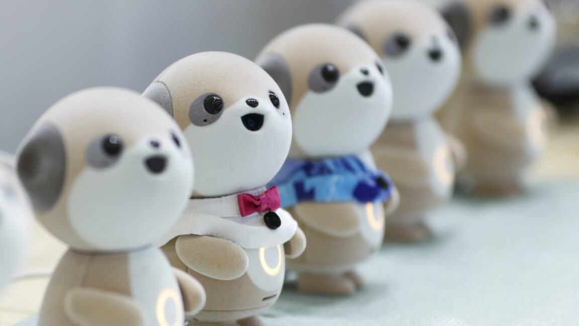 Four plastic anthropomorphic toy dogs are lined up on display at a trade show.
