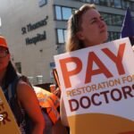Resident doctors on strike hold placards outside St. Thomas's hospital in London